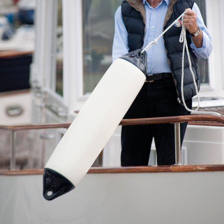 Polyform F2 fender på stranden med båd i baggrunden